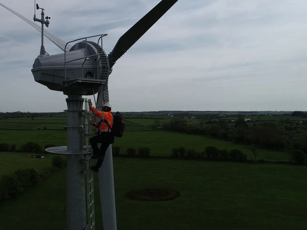 The nacelle and its sensor mast, with a technician on the ladder