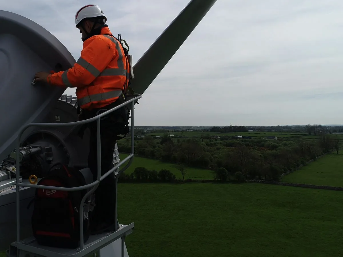 A technician on the working platform opening the hinged top cover of the nacelle